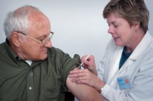femeie care injectează o seringă pe brațul omului